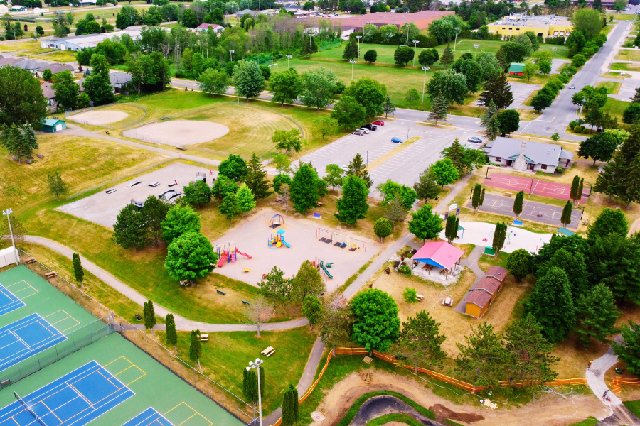 Aerial view of outdoor recreation complex, includes playground, tennis courts, baseball diamond, and parking lot