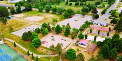 Aerial view of outdoor recreation complex, includes playground, tennis courts, baseball diamond, and parking lot