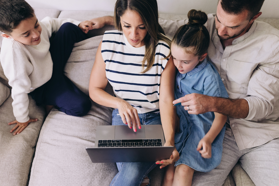 Family sitting on couch looking at laptop