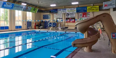 Indoor community pool looking towards deep end, with water slide on the right