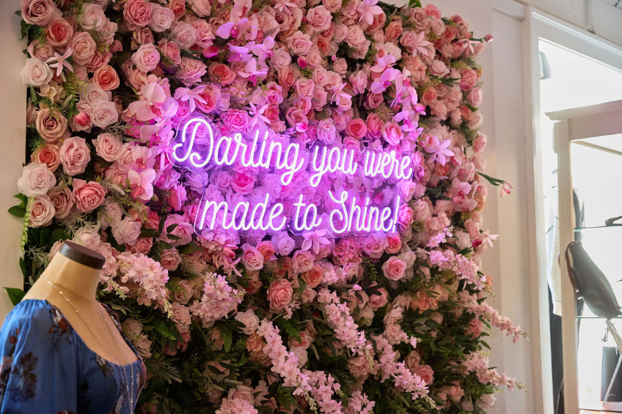 Floral backdrop with pick neon sign that says "Darling, you were made to shine"