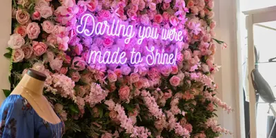 Floral backdrop with pick neon sign that says "Darling, you were made to shine"